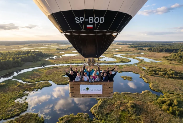 Uśmiechnięta grupa pasażerów w koszu balonu SP-BOD podczas lotu widokowego nad rozlewiskami Narwi i Biebrzy – Loty Balonowe Podlasie.